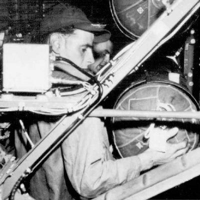 Containers, with parachute packs attached, are stored in the bomb racks within the B-24 aircraft
